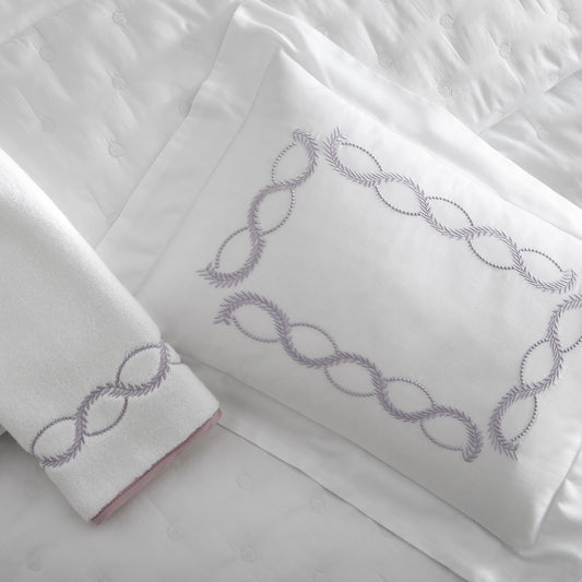 Home Treasures Calista Embroidery in Incenso Lavender, shown on a white Royal Sateen sham and Izmir terry towel, with a Cerchio quilted backdrop in White.