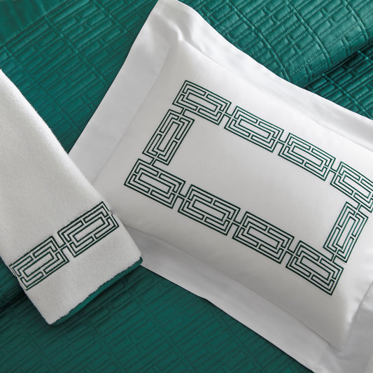 Home Treasures Felix Embroidery in Emerald, shown on a white Royal Sateen sham and Izmir terry towel, with a Sydney quilted backdrop in Emerald.