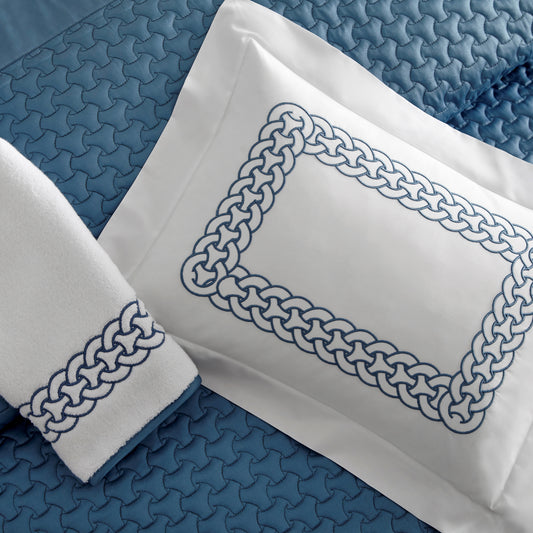 Home Treasures Links Embroidery in Slate Blue, shown on a white Royal Sateen sham and Izmir terry towel, with a Trinity quilted backdrop in Slate Blue.