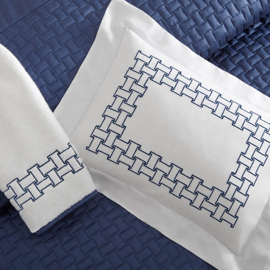 Home Treasures Sawyer Embroidery in Navy Blue, shown on a white Royal Sateen sham and Izmir terry towel, with a Basketweave quilted backdrop in Navy Blue.