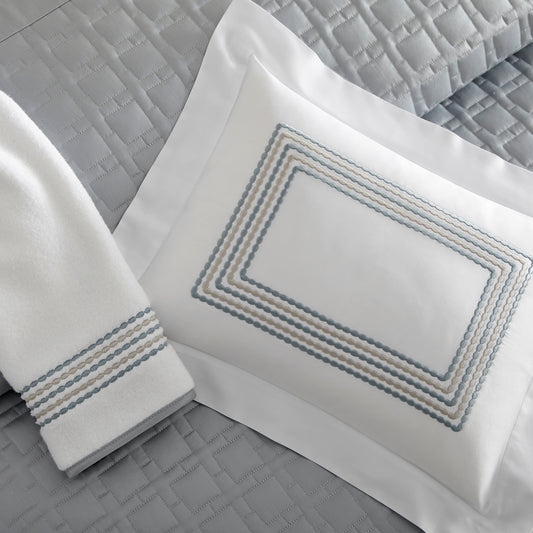 Home Treasures Stella Embroidery in Horizon, shown on a white Royal Sateen sham and Izmir terry towel, with a Square quilted backdrop.