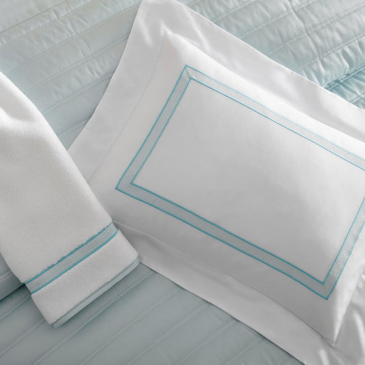 Home Treasures Sutton Embroidery in Frost, shown on a white Royal Sateen sham and Izmir terry towel, with a L'Avenue quilted backdrop in Ice.